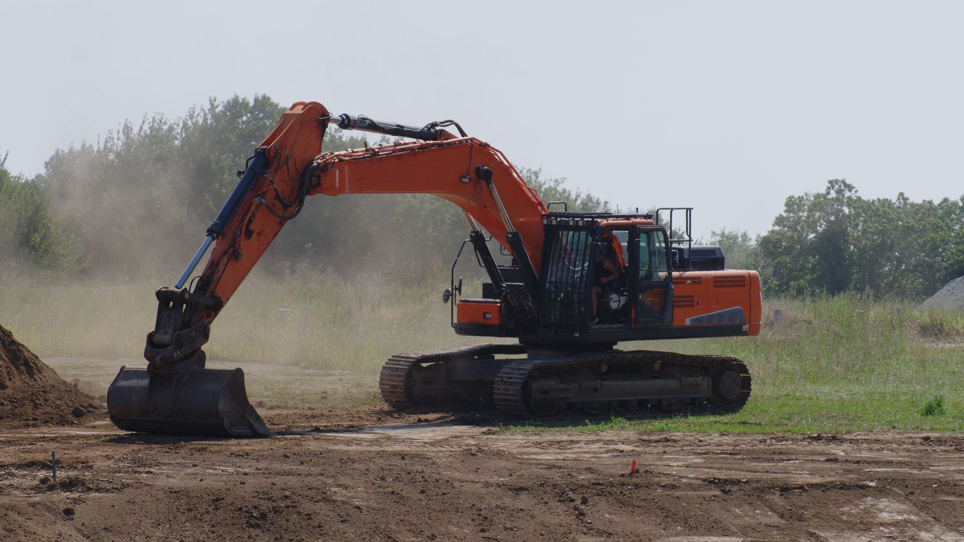 Orangefarbener Bagger bei Erdarbeiten auf einer Baustelle