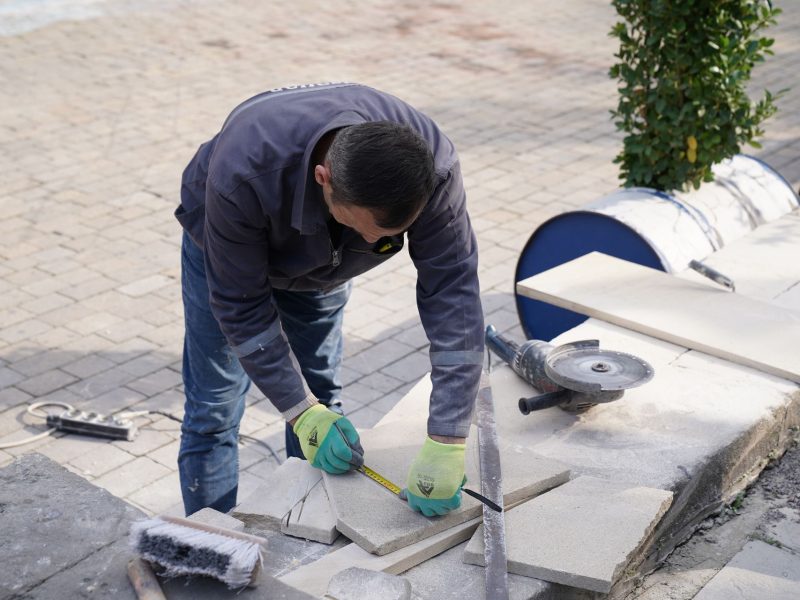 Handwerker schneidet Terrassenplatten zu und verlegt sie